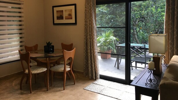A dining area with a table and chairs, a framed picture on the wall, and a view of the outdoors through a glass door.