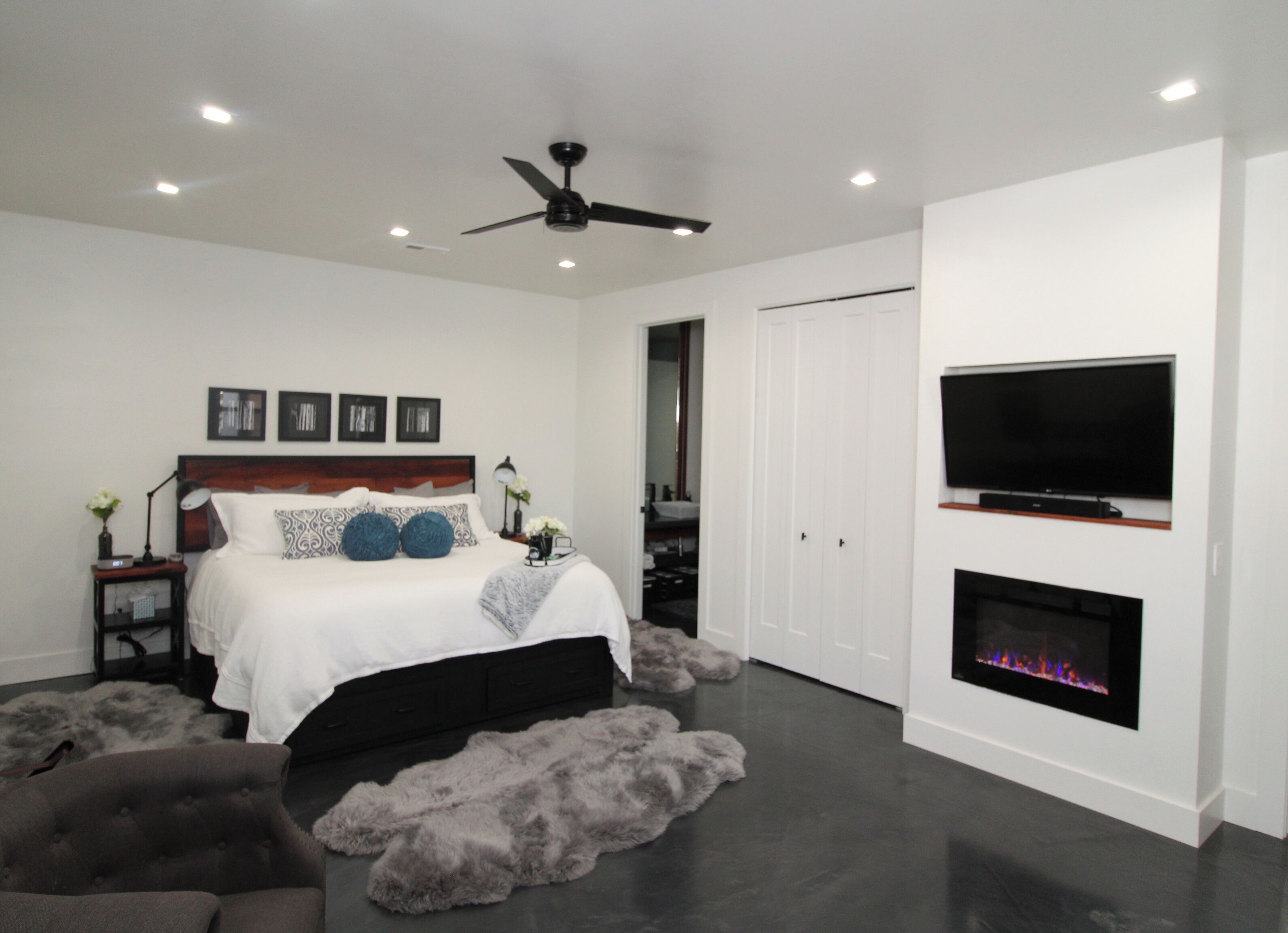 Une chambre à coucher moderne avec un lit, un ventilateur de plafond, une télévision et une cheminée.