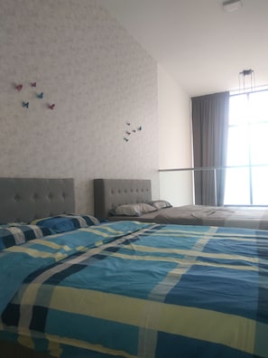 A bedroom with a large bed, a headboard, and a window with curtains.