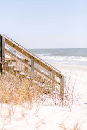 Walk along the beach on a weathered boardwalk leading to the ocean.