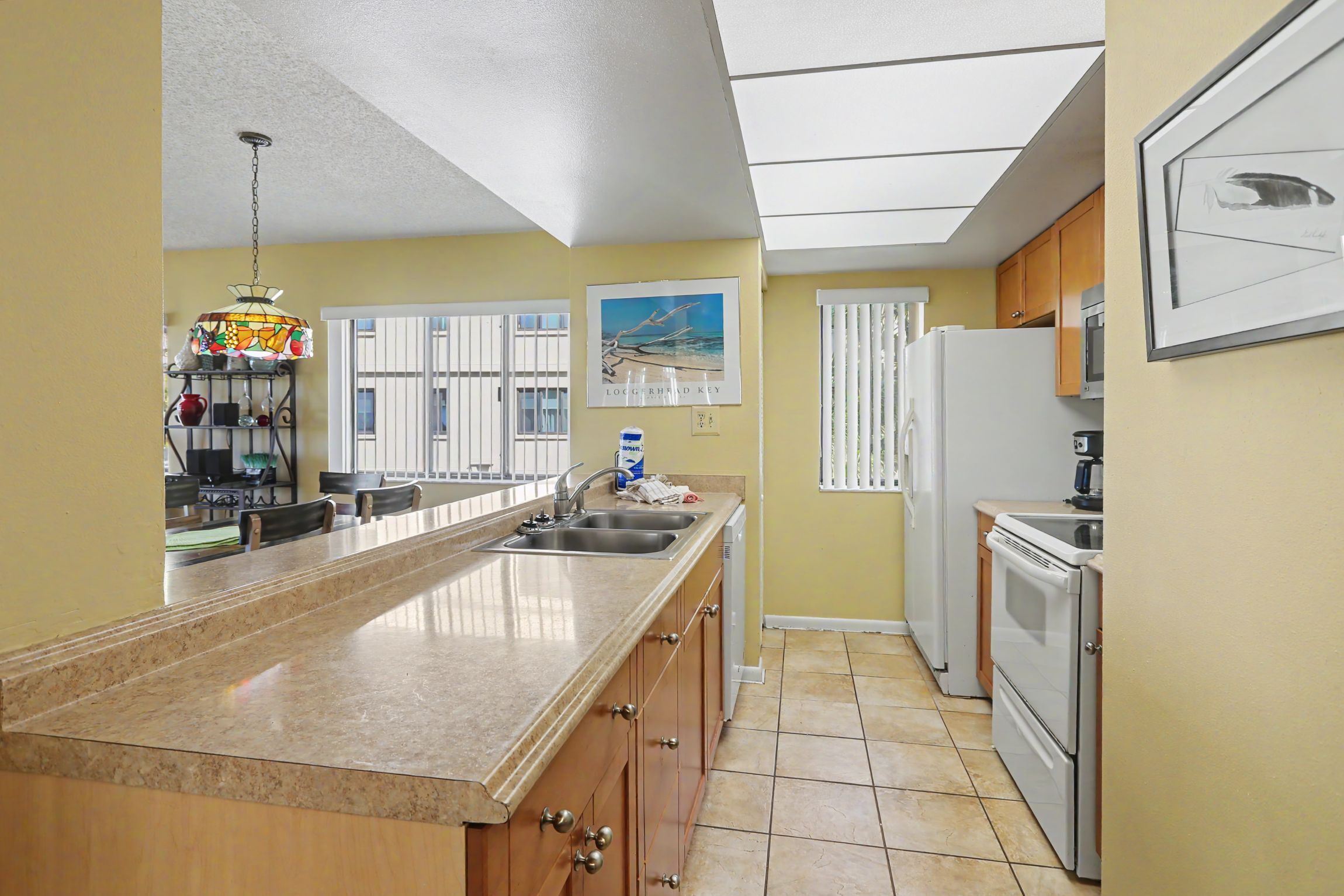 A kitchen with a long countertop, a refrigerator, and a microwave.