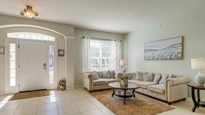 A living room with a beige sofa set, a coffee table, a rug, a lamp, and a painting on the wall.