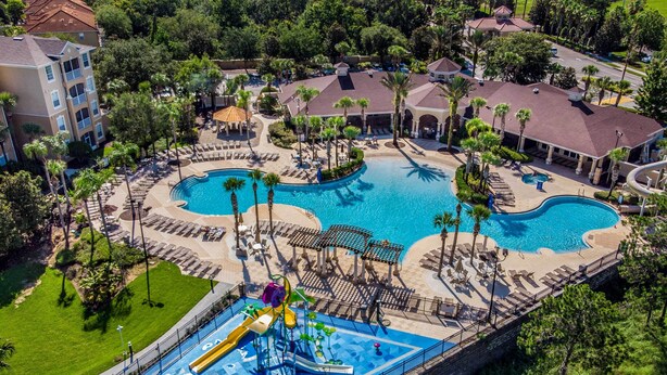 An aerial view of a resort with multiple swimming pools, a water park, and surrounding greenery.