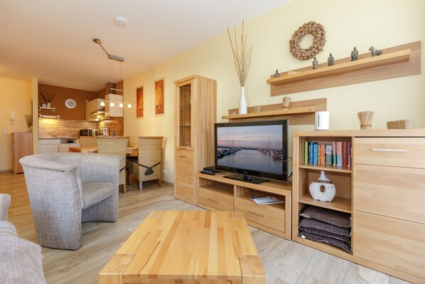 A modern living room with a wooden coffee table, a TV, and a bookshelf. - Apartment near the beach at the marina (Kühlungsborn)