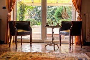 Ein Zimmer mit zwei Ledersesseln, einem kleinen Tisch mit Tassen und Blick durch ein großes Fenster.