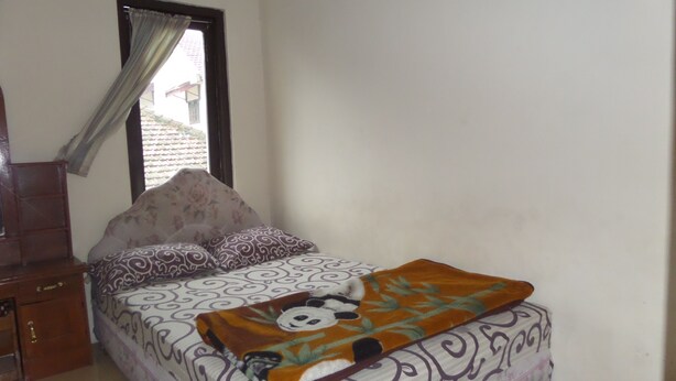 A bedroom with a bed, a window with curtains, a wooden dresser, and a tiled floor. - Villa Anna (Ngadisari)