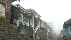 A narrow cobblestone street flanked by traditional buildings with stone walls and tiled roofs. - Villa Anna (Ngadisari)