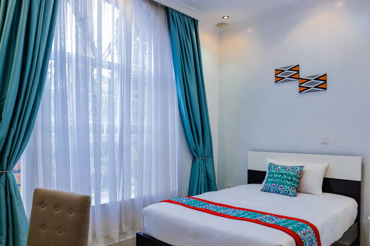 Una habitación de hotel con una cama, una silla y cortinas.