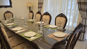 Une table à manger dressée pour huit personnes, avec des chaises, des bouteilles d’eau et des verres à vin.