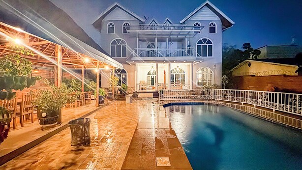 Une grande maison à deux étages, dotée d’une piscine, d’un espace extérieur aménagé et d’une terrasse couverte.
