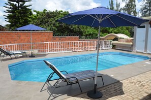 Een buitenzwembad, parasols voor strand/zwembad