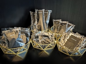 A display of gift bags with various items labeled, arranged in a geometric pattern on a reflective surface. - Hotel 31 (Funabashi)