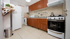 Eine Küche mit Holzschränken, einem weißen Kühlschrank, einem Herd und einer Waschmaschine.