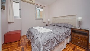 Ein Schlafzimmer mit einem Bett, einem Nachttisch, einer Lampe und einer roten Bank.