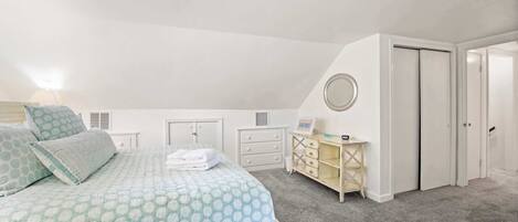 A bedroom with a bed, a dresser, a mirror, and a door.