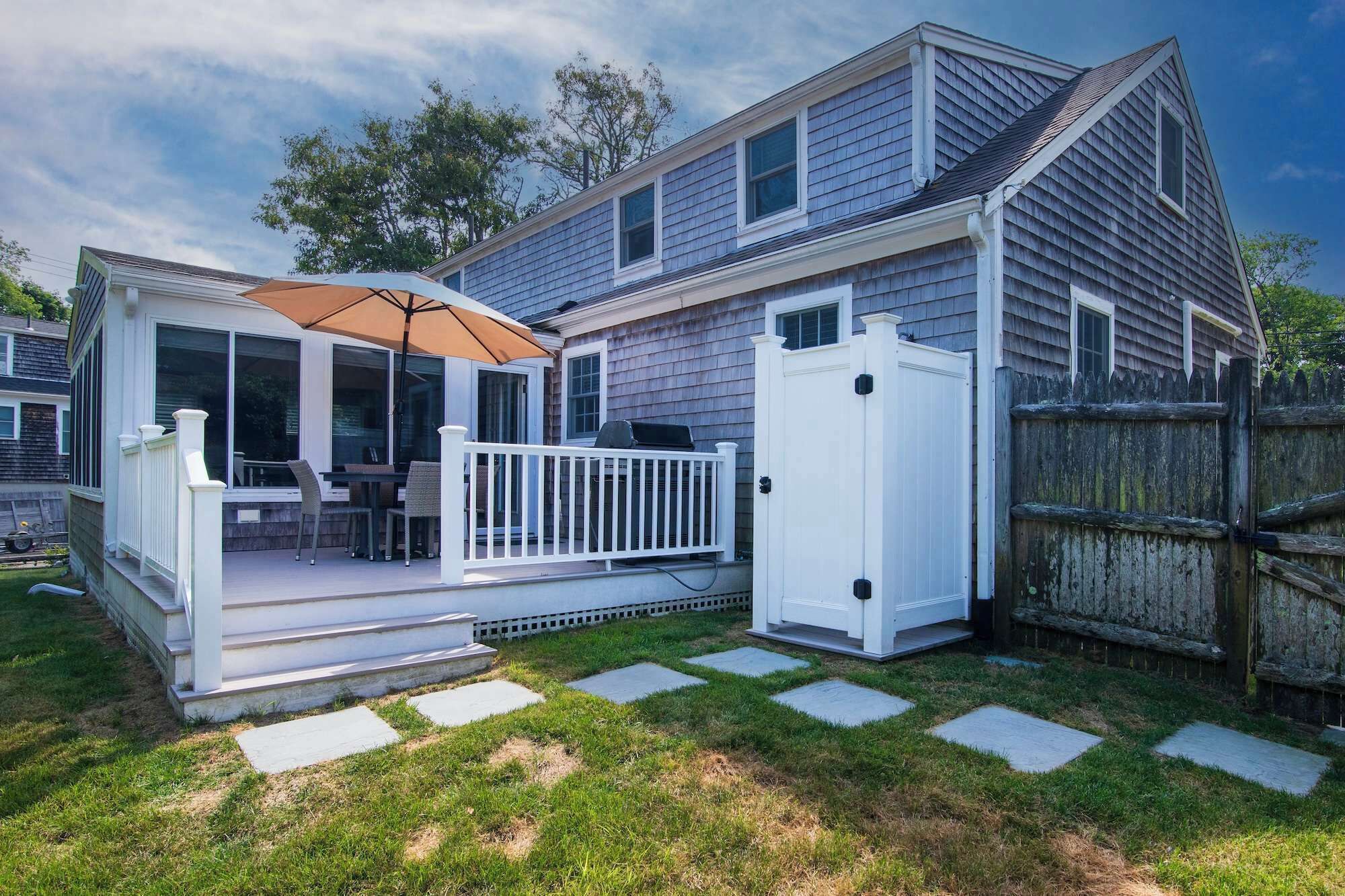A house with a covered patio, a fenced yard, and a wooden deck.