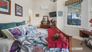 Une chambre à coucher avec un lit, une commode, un téléviseur et une fenêtre donnant sur un beau paysage.