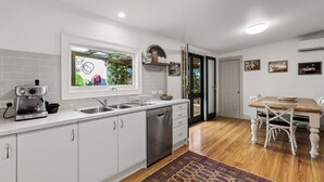 A modern kitchen with white cabinets, a built-in oven, and a coffee machine. - The Other House (Piccadilly)