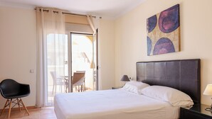 Ein Schlafzimmer mit Bett, Sessel, Nachttisch und einem Bild an der Wand.