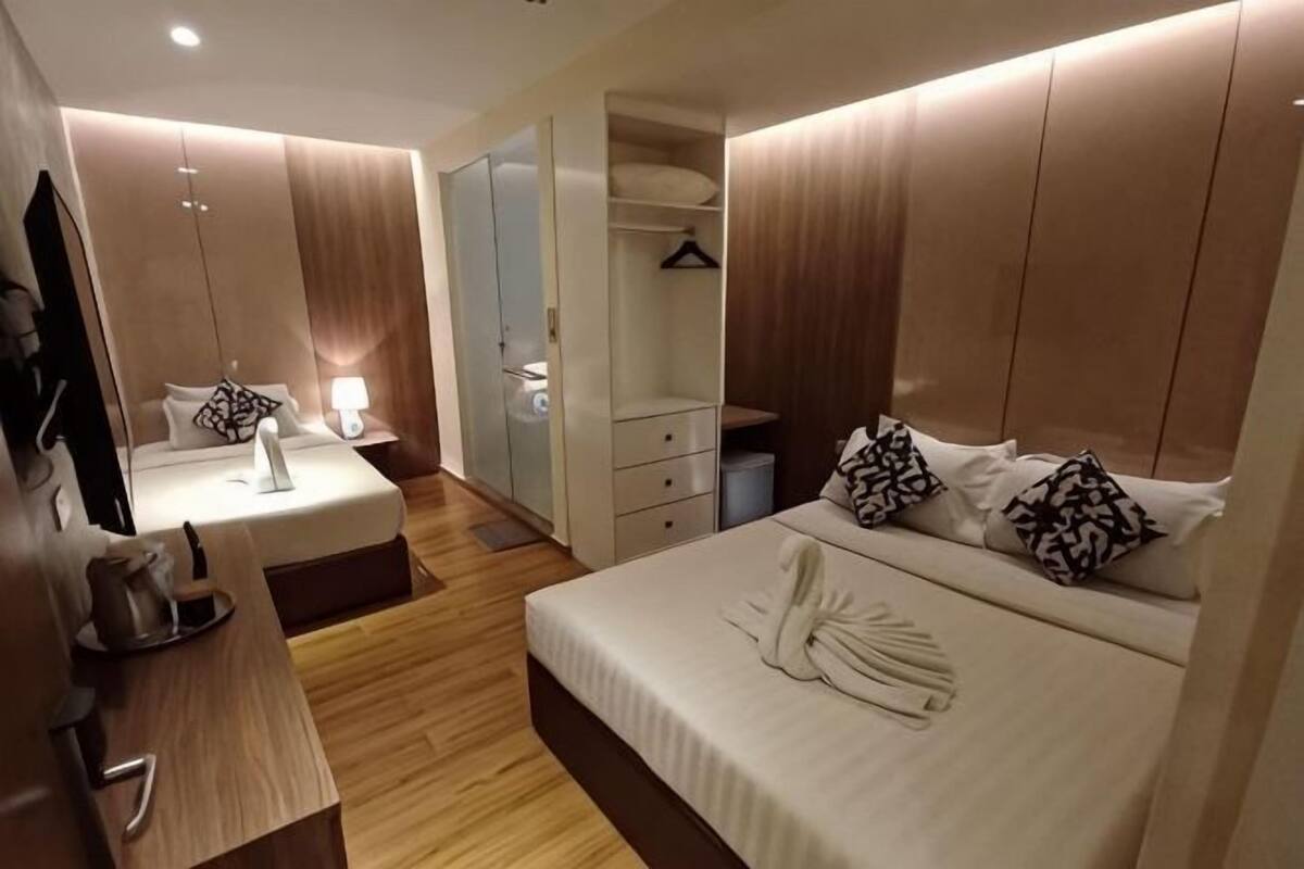 A modern hotel room with a bed, bedside table, wardrobe, and a mirror.