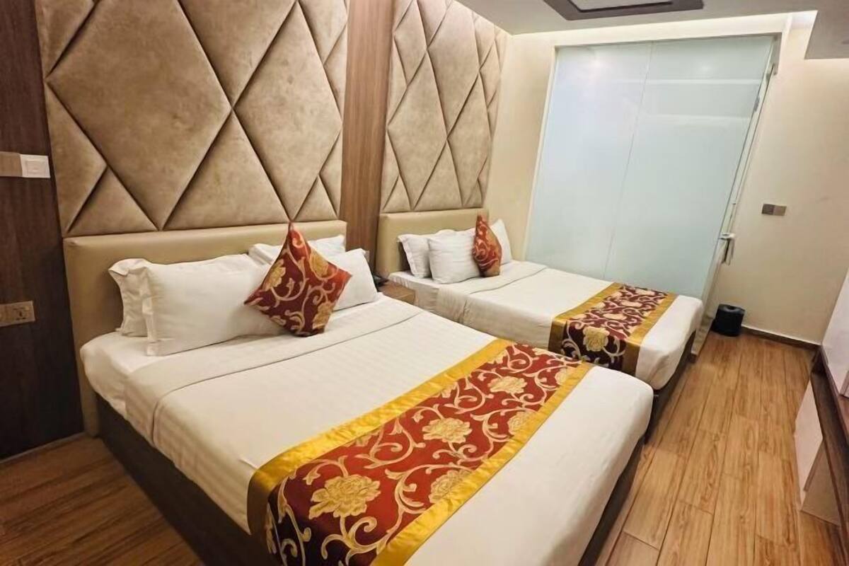 A hotel room with two beds, a large padded headboard, and a small closet.