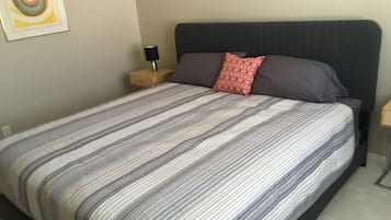 Ein Bett mit gestreifter Bettdecke, einem dunklen Kopfteil und einem Nachttisch mit Lampe.