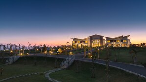 A modern hotel with a spacious outdoor area, a well-maintained lawn, and a curved pathway leading to the entrance. - SkyeBay Club (Hengchun)