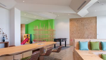 Enjoy communal dining and leisure activities in this modern space featuring a dining table, foosball table, and cozy seating area.