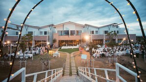 An outdoor wedding venue with a central aisle leading to a building, surrounded by tables and guests. - SkyeBay Club (Hengchun)