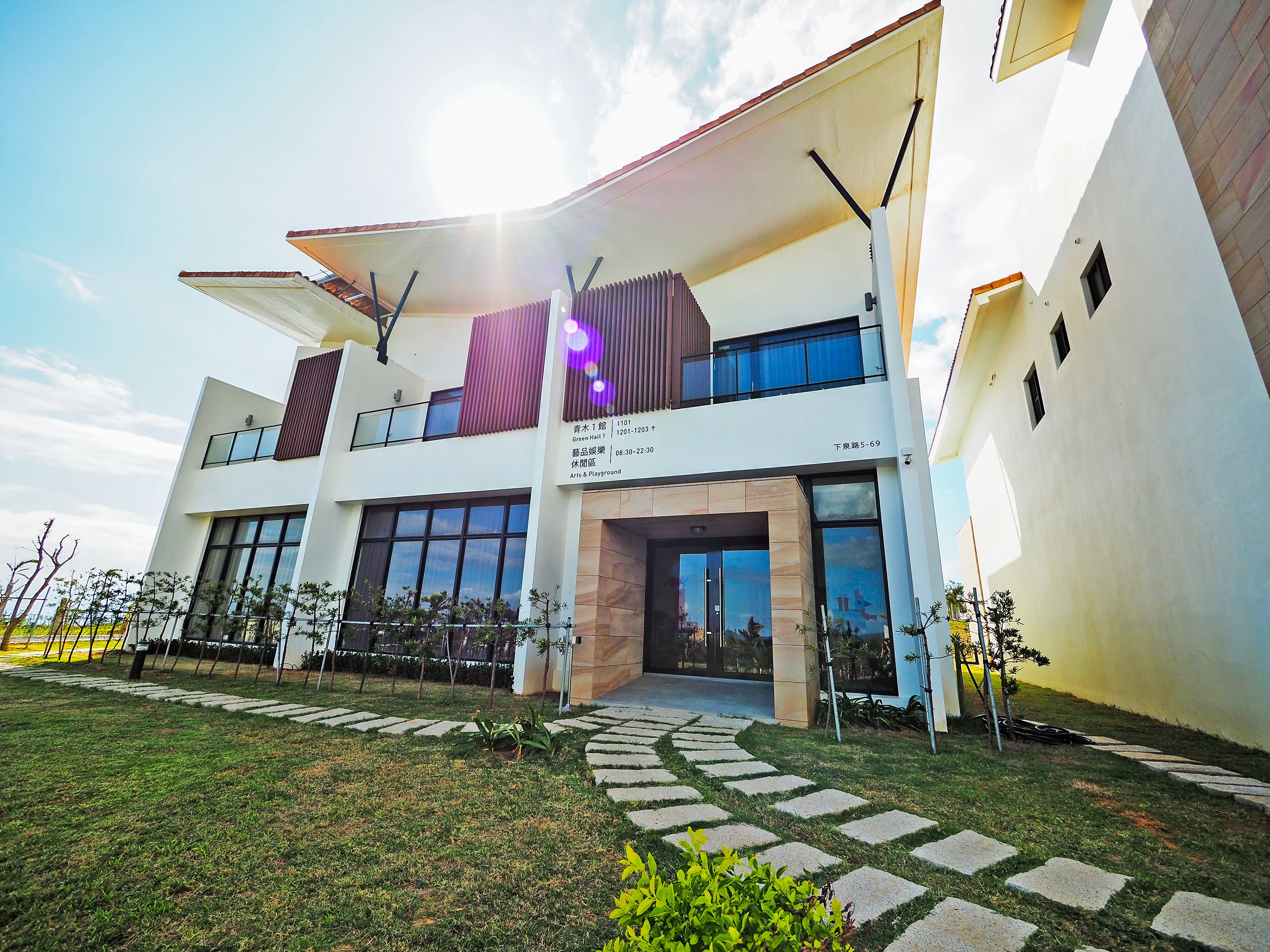 A modern building with a two-story structure, large windows, and a covered entrance.