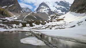 Un paisaje montañoso con picos nevados y un lago congelado.