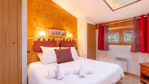 Un dormitorio con paneles de madera, una cama, almohadas y toallas.