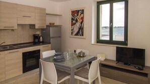 A modern kitchen with a dining area, a painting, and a view of the sea. - A seafront, one bedroom apartment with big terrace - Umag Center 1 (Umag)