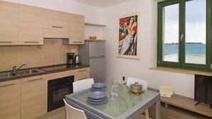 A modern kitchen with a dining area, a view of the sea, and a painting on the wall. - A seafront, one bedroom apartment with big terrace - Umag Center 1 (Umag)