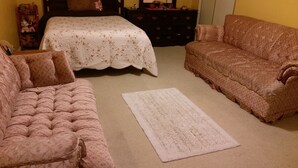 Une pièce comprenant un lit, deux canapés, une commode et un tapis.