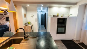 Eine moderne Küche mit schwarzem Arbeitsplatz, Spüle aus Edelstahl und eingebautem Backofen.