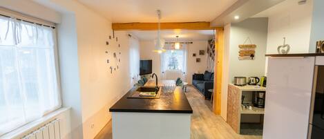 A modern kitchen with a central island, a dining area with a sofa, and a kitchen counter with appliances.