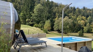 Un pontile in legno con piscina, sedie a sdraio e vasca idromassaggio.