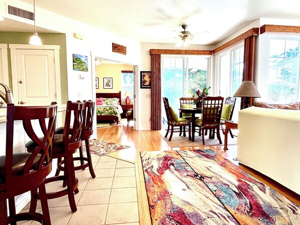 A spacious room with a large bed, a dining area with chairs and a table, and a view through the windows. - Huge Fall Discounts! Our Dreamy Oasis at the Plantation at Princeville (Princeville)