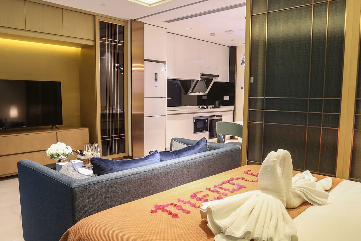 Een hotelkamer met een bed, een bank, een televisie, een kitchenette en een schuifdeur.