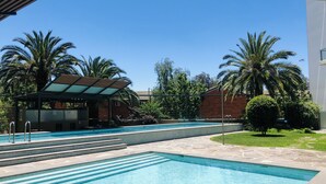 A swimming pool with tiled steps leading into it, surrounded by palm trees and a covered pavilion. - Staying Places - The Avenue (Turner)
