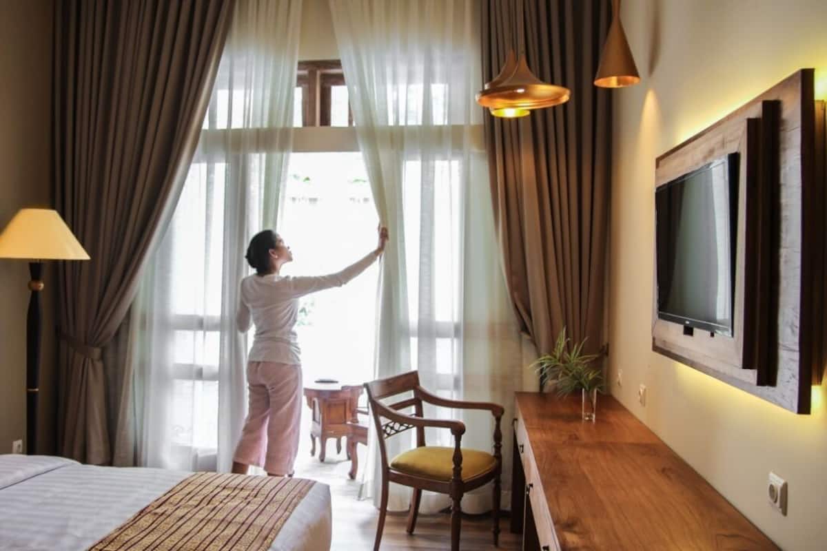 A hotel room with a bed, a desk, a chair, a TV, and curtains.