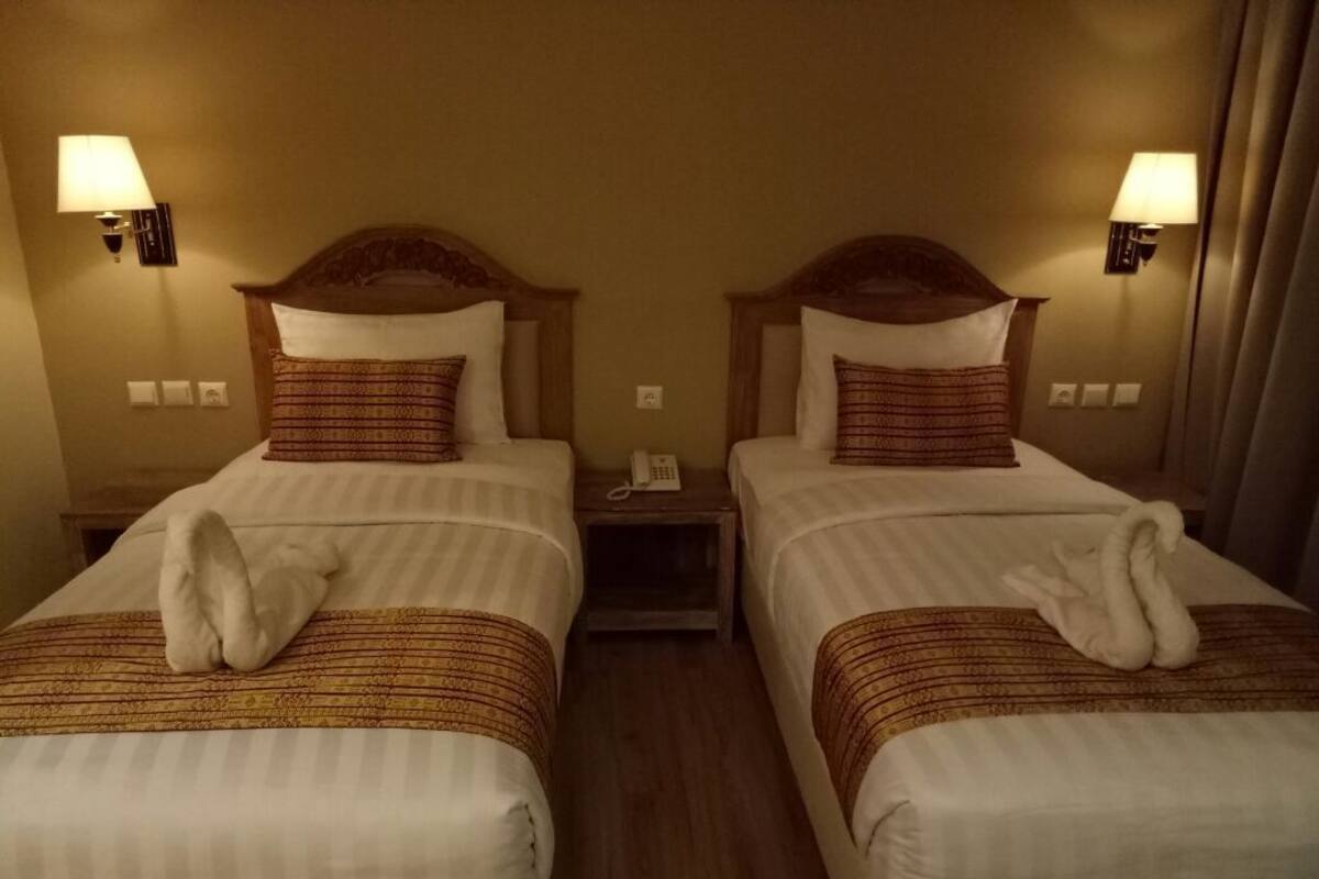 Two single beds with headboards, bedside lamps, and a telephone on a wooden nightstand.