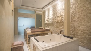 A modern bathroom with a large bathtub, a wooden vanity, and a stone accent wall. - Ndalem Nuriyyat Villas & Spa (Ngaglik)
