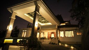 A modern house with a covered porch, stone pillars, and a well-lit entrance. - Ndalem Nuriyyat Villas & Spa (Ngaglik)