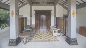 A traditional interior with a central wooden door, ornate chairs, a chandelier, and patterned flooring. - Ndalem Nuriyyat Villas & Spa (Ngaglik)