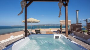 Une terrasse sur le toit avec un jacuzzi, des chaises longues et une vue sur la mer.