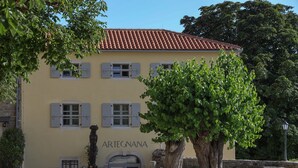 A yellow building with the name "ARTEGNANA" on the facade, a stone wall, and a large tree in the foreground. - B&B Artegnana 1798 (Groznjan)