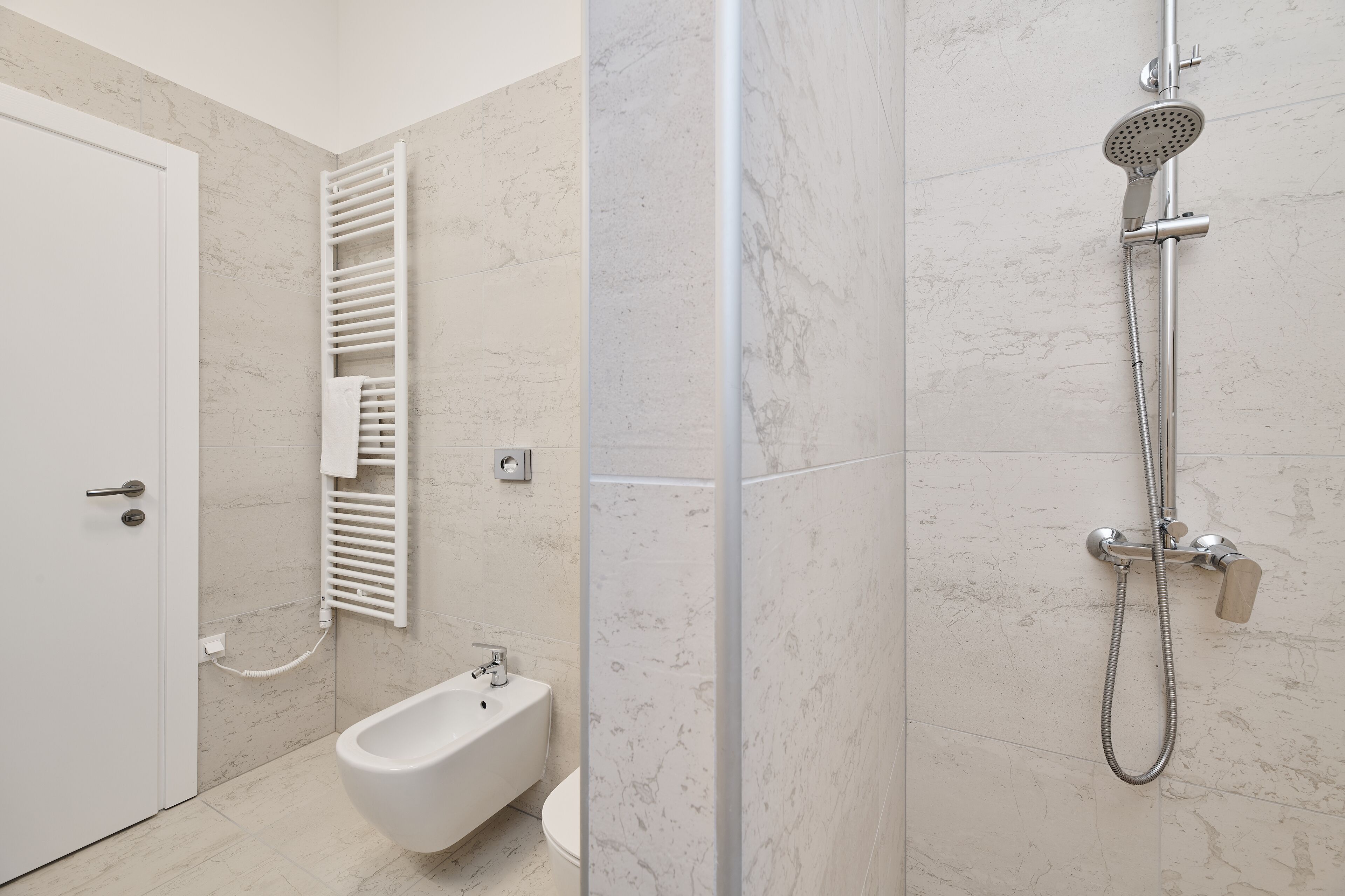Un bagno moderno con un bidet, una doccia e una porta bianca.
