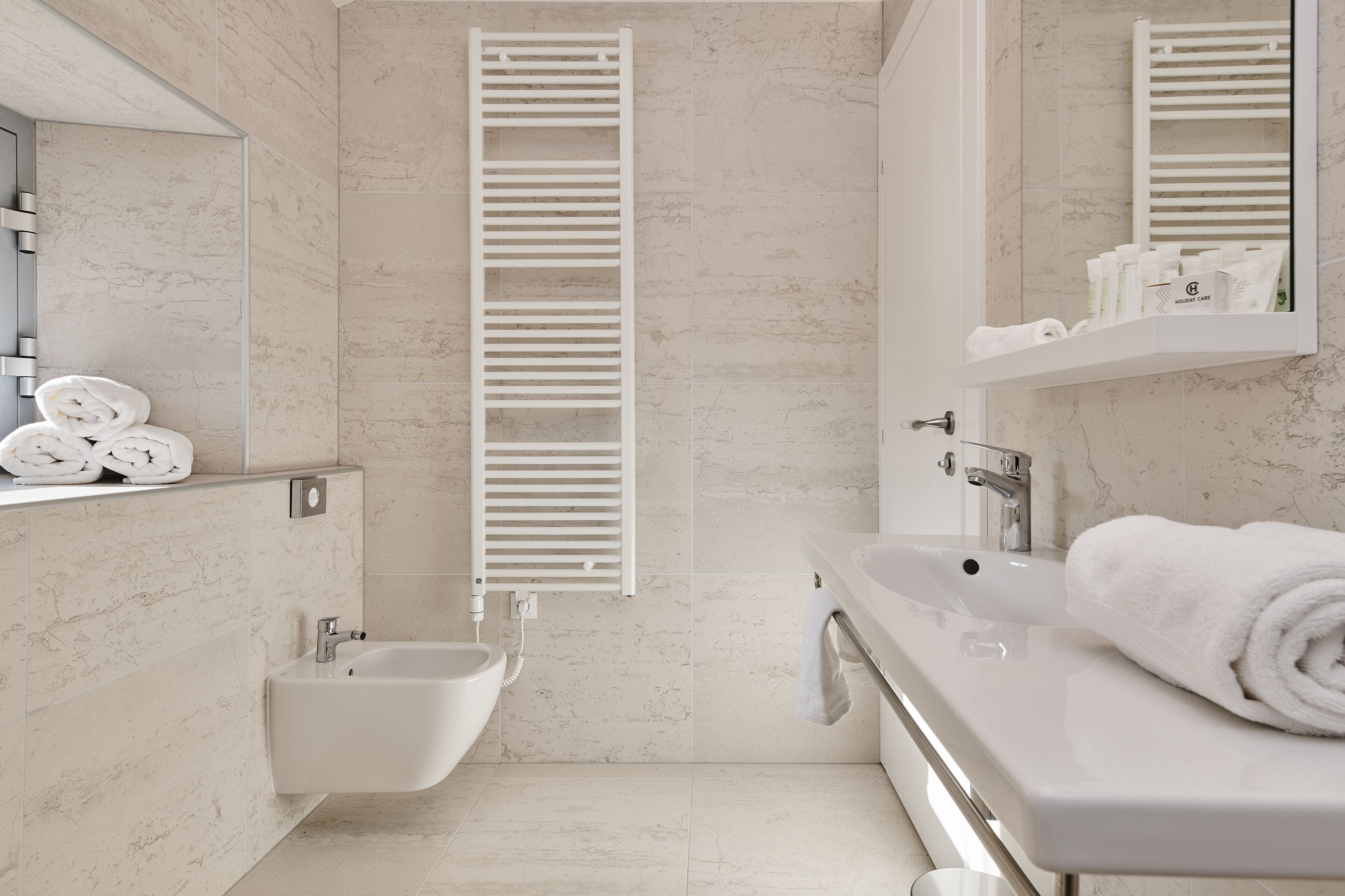 Un baño moderno con un bidé, un lavabo y un espejo.